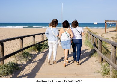 Three Women Walking Across A Bridge On The Beach