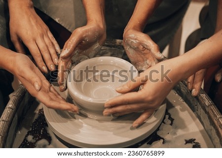 Three women are working on a potter's wheel, making a vase. Close up picture.