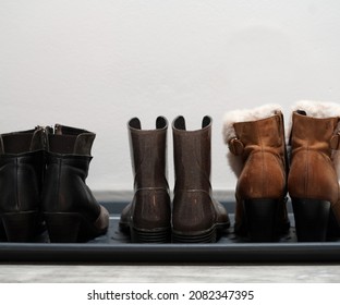 Three Women's Shoes. They Are Lined Up In A Bright Hallway. They Have Different Colors. Some Are Leather And Some Rubber. Some Are On A Mild Heel.