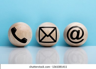 Three Wooden Ball With Contact Icon Arranging In A Row Over Reflecting Floor