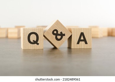 three wooden blocks with letters QA with focus to the single cube in the foreground in a conceptual image, grey background, question and answer concept - Shutterstock ID 2182489061