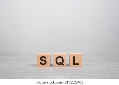 Three Wooden Blocks With The Letters SQL On The Bright Gray Table. Business Concept. SQL - Short For Structured Query Language