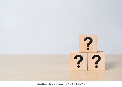 Three wooden cube block shape with sign question mark symbol on wood table