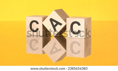 three wooden cubes with acronym CAC on yellow background. reflection of an image on a glass surface concept