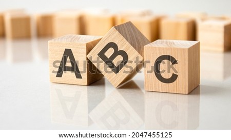 Three wooden cubes with the letters ABC on the bright surface of a gray table. the inscription on the cubes is reflected from the surface of the table. business concept.