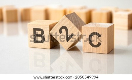 Three wooden cubes with the letters B2C on the bright surface of a gray table. the inscription on the cubes is reflected from the surface of the table. b2b - short for business to consumer