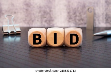 three wooden cubes with letters BID, on white table and diagram, business concept