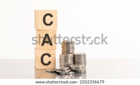 three wooden cubes with letters CAC, on white table and diagram, business concept. CAC - short for customer acquisition cost