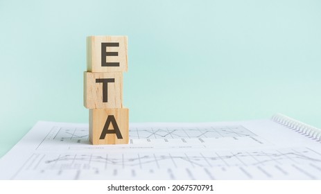 three wooden cubes with letters ETA, on white table and diagram, business concept. ETA - short for ESTIMATED TIME OF ARRIVAL