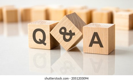 Three wooden cubes with the letters Q and A on the bright surface of a gray table. the inscription on the cubes is reflected from the surface of the table. Q and A - short for question and answer - Shutterstock ID 2051203094