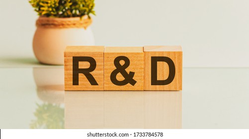 Three wooden cubes with letters R and D on white board. Flower in the background on the left.