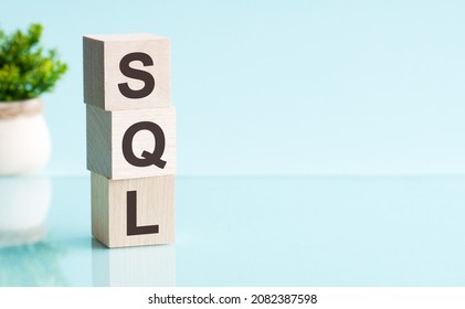 Three Wooden Cubes With Letters - SQL - Short For Structured Query Language, On Blue Table, Space For Text In Right. Front View Concepts, Flower In The Background.