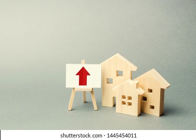 Three Wooden Houses And A Red Up Arrow On The Sign. Real Estate Value Increase. High Rates Of Construction, High Liquidity. Supply And Demand. Rising Prices For Housing, Building Maintenance.