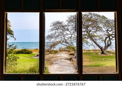 Three wooden window frames looking out to the bright blue sea and sky.