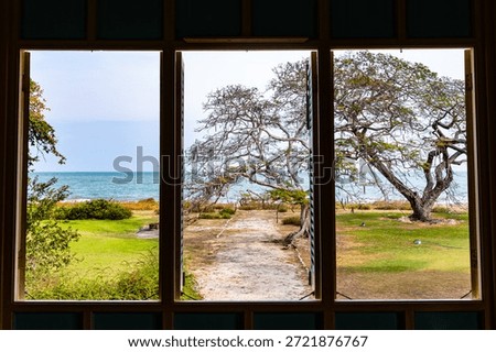 Three wooden window frames looking out to the bright blue sea and sky.