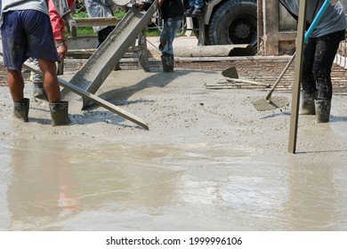 three worker team working wet cement truck on floor by use trowel with long Tools spreading poured concrete for strong street after dry.