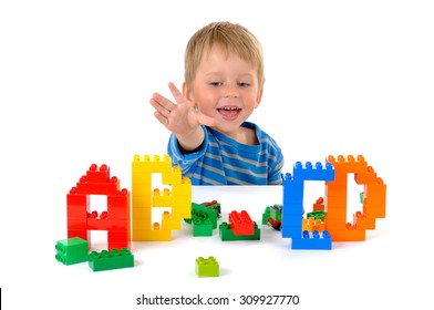 The three year child playing with letters on the table isolated on white