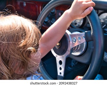 A Three Years Old Toddler Enjoys Playing Like He Is Driving A British Classic Car