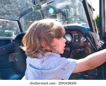 A Three Years Old Toddler Enjoys Playing Like He Is Driving A British Classic Car