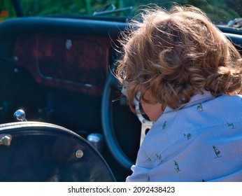 A Three Years Old Toddler Enjoys Playing Like He Is Driving A British Classic Car