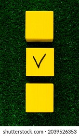 Three Yellow Cubes With A Tick On One On Grass. Concept Of Choosing A Better Option, Creating Checklists, Elections And Sports Betting