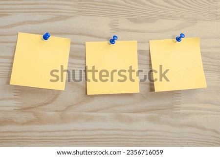 Three yellow paper notes mockup pinned to wooden bulletin board. sticky notes on bulletin board. Three sticker with push pins on wooden background