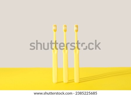 Three yellow toothbrushes on color background.