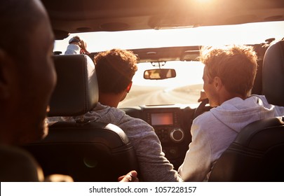 Three Young Adult Men Driving In A Car With Sunroof Open