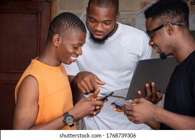 three young african people using their mobile phones and laptops simultaneously sharing content