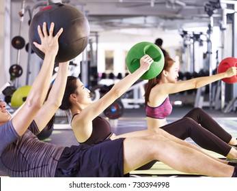 three young asian adult people working out in fitness center using medicine balls. - Powered by Shutterstock