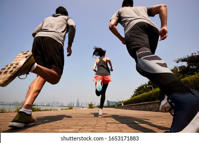 Three Young Asian Adults Running Jogging Outdoors, Rear And Low Angle View
