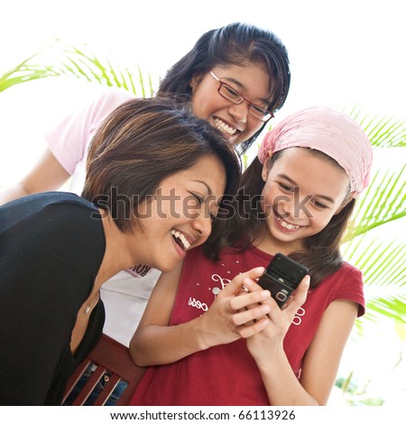 Three young Asian girls sharing a laughter while using a mobile phone