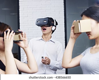 Three Young Asian People Wearing Different Types Of Virtual Reality (VR) Goggles.