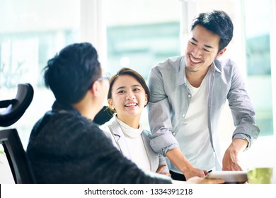 Three Young Asian Teammates Working Together Having A Pleasant Business Discussion In Office.