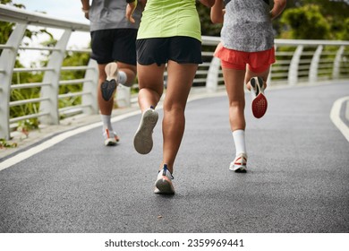 three young asian women female joggers exercising outdoors together in city park - Powered by Shutterstock