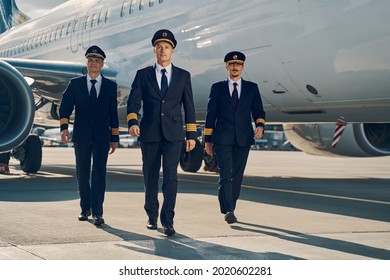 Three young aviators walking across the aerodrome