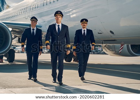 Three young aviators walking across the aerodrome