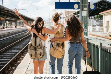Three young beautiful female women at station to catch train for their vacation together during Coronavirus Covid-19 pandemic wearing protective face masks - Millennials have fun during the holidays