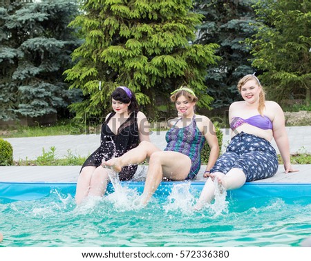 Three young beautiful plus size model splashing in the pool outdoors. Professional makeup and hairstyle, xxl woman portrait. 