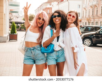 Three young beautiful smiling female in trendy summer clothes.Sexy carefree multiracial women posing on the street background.Positive models having fun in sunglasses. Cheerful and happy