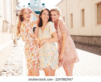 Three young beautiful smiling hipster female in trendy summer dresses  clothes. Sexy carefree women posing in the street. Positive models having fun outdoors at sunny day. Cheerful and happy