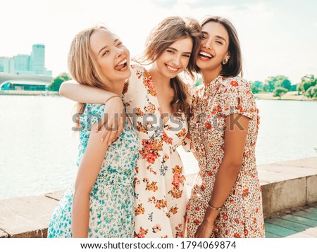 Three young beautiful smiling hipster girls in trendy summer sundress.Sexy carefree women posing on the street background. Positive models having fun and hugging.Walking after shopping