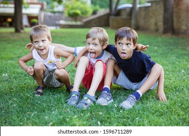 Three Young Boys Making Weird Grimace Faces In Summer Park. Friends Or Siblings Having Fun Outdoors.