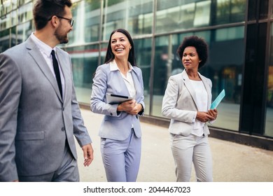 Three young business people talking to each other while walking outdoors.