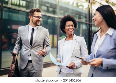 Three young business people talking to each other while walking outdoors. - Powered by Shutterstock