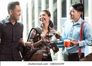 Three Young And Cheerful Employees Wearing Trendy Casual Clothes While Talking Together In The Morning In A Modern Workplace 