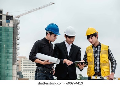Three young engineer Talking to a worker in building site