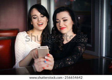 Three young female friends taking a picture of themselves on a smart phone. Hispanic, selfie