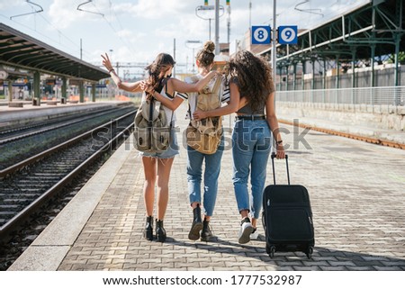 Three young friends women at the station walking and waiting train for their trip in summer with face mask for protection by infection from Coronavirus, Covid-19 - Millennials having fun together