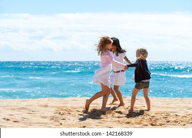 Three young girlfriends playing game on beach.